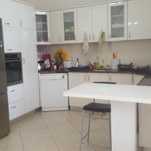 מטבח מודרני עם ארונות לבנים ומכשירי חשמל