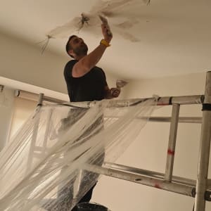 חשמלאי עובד על תקרה עם חוטי חשמל חשופים