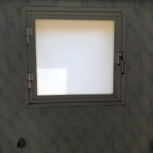 חלון זכוכית עם מסגרת לבנה על קיר בהיר