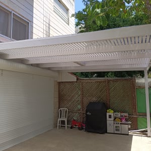 פרגולה מאלומיניום לבנה בחצר עם צל חלקי