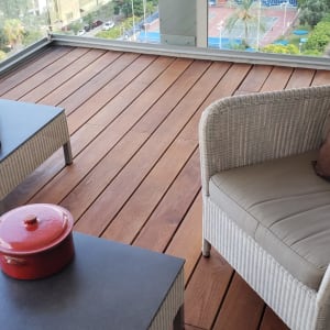 רצפת עץ עם רהיטי גן וסיר אדום על שולחן