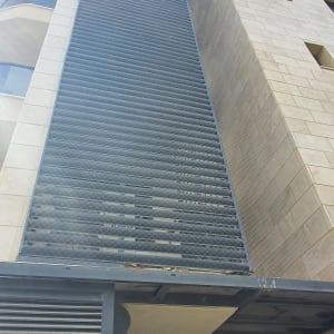 רשת מתכת על קיר בניין למניעת כניסת יונים