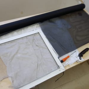 מסגרת חלון עם רשת קרועה וכלים לתיקון תריסים