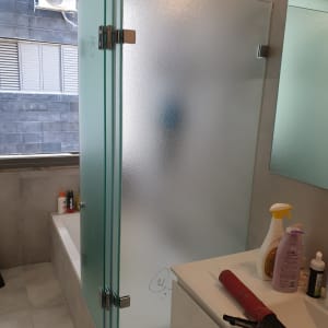 דלת זכוכית חלבית במקלחת עם צירים מתכתיים