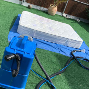 מכונת ניקוי כחולה ליד מזרן על דשא