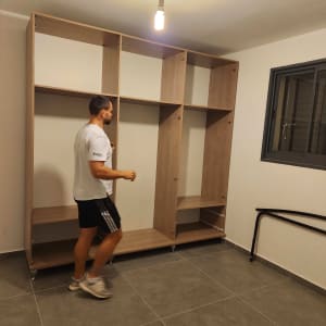 אדם מרכיב ארון עץ בחדר ריק