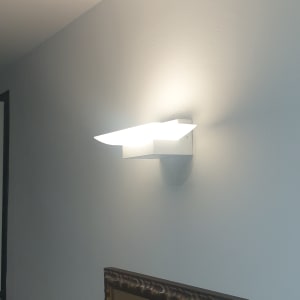 מנורת קיר מוארת על קיר לבן