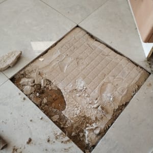 רצפה עם אריח שבור ועבודת תיקון בעיצומה