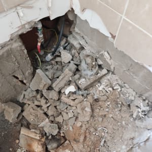 צינור מים חשוף בקיר שבור עם ברז אדום