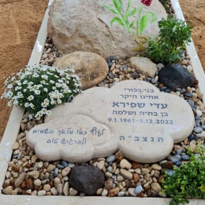 קבר עם אבן גדולה ופרחים צבעוניים