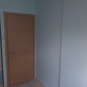 קיר צבוע בצבע כחול בהיר ליד דלת עץ