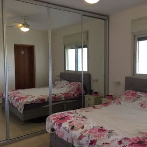 חדר שינה עם ארון מראות ומיטה זוגית