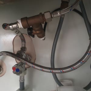 צינורות מתכת מחוברים לברזים מתחת לכיור