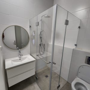 מקלחון זכוכית עם ראש מקלחת עגול ומוט מתכוונן