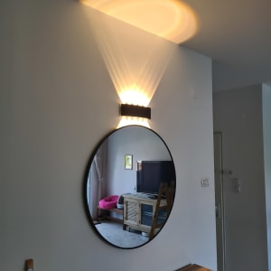 מראה עגולה על קיר עם מנורה מעליה