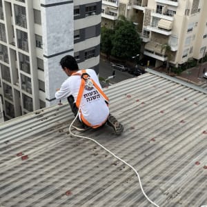 אדם עם רתמה על גג מתכת עם חבל