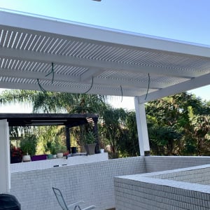 פרגולה לבנה עם עציצים על קיר מרפסת