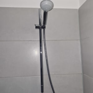 ראש מקלחת מותקן על קיר אריחים אפור