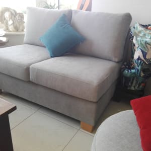 ספה אפורה עם כרית כחולה על רגלי עץ