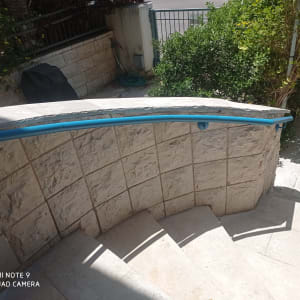 מעקה כחול על קיר אבן במדרגות חיצוניות