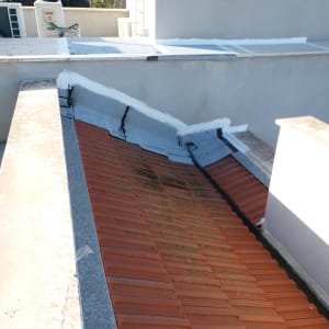 איטום גג עם חומר לבן על קצוות רעפים