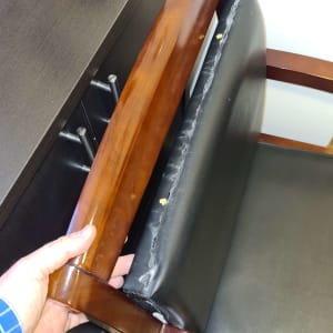 יד מחזיקה כיסא עץ עם ריפוד שחור קרוע