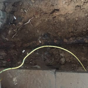 צינור מים ישן באדמה עם חוט חשמל צהוב