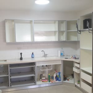 מטבח בשיפוץ עם ארונות פתוחים וכלים על השיש