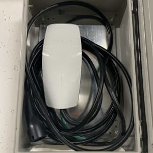 מטען טסלה עם כבל חשמלי בתוך ארון מתכת