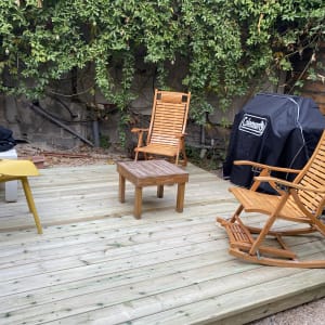 דק עץ עם כיסאות נדנדה ושולחן קטן