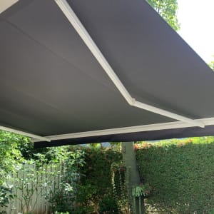 סוכך בד כהה עם מסגרת מתכת לבנה בגינה