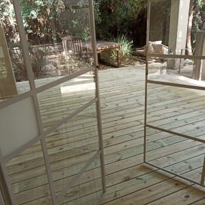 דק עץ בגינה עם דלת זכוכית פתוחה