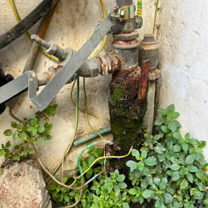 צינור חלוד עם חיבורים וכלים ליד קיר