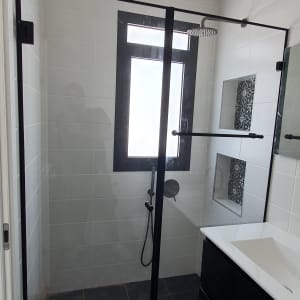 מקלחון זכוכית עם ראש מקלחת עגול וקיר אריחים