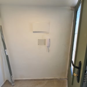 אינטרקום מותקן על קיר לבן ליד דלת ירוקה