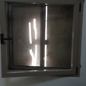 חלון עם תריסים סגורים וידית שחורה בצד שמאל