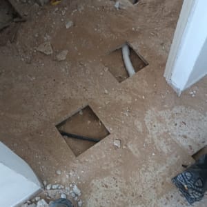 רצפה עם חורים וצינורות חשופים בעבודת אינסטלציה