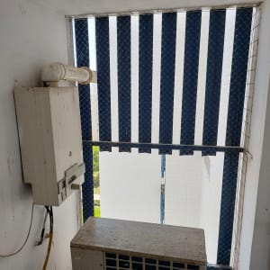 רשת הגנה נגד יונים על חלון עם תריסים כחולים