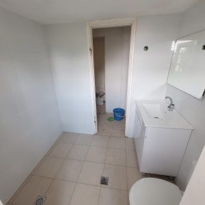 חדר אמבטיה עם כיור, אסלה ודלי כחול על הרצפה