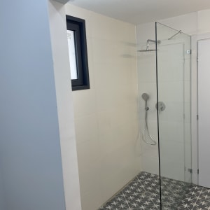 מקלחון עם דלת זכוכית ורצפת אריחים מעוצבת