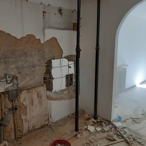 שני עמודי תמיכה, קיר שבור ודלי עם פסולת בנייה