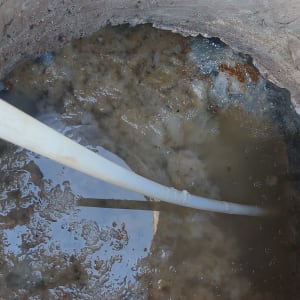 צינור לבן בתוך בור ביוב עם מים עכורים