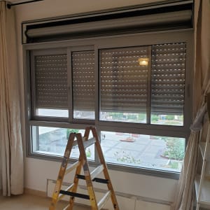 תריסים סגורים על חלון עם סולם עץ לידם