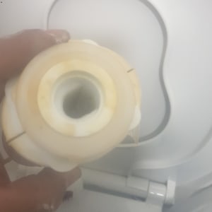 יד מחזיקה חלק פלסטיק מול אסלה לבנה