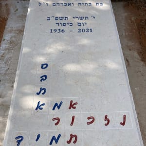 מצבה עם כיתוב בעברית ותשבץ אותיות צבעוני