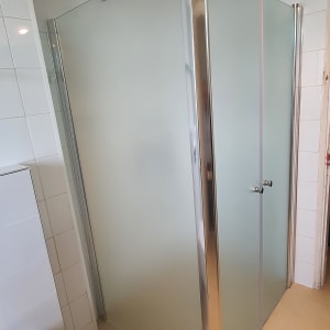 מקלחון זכוכית עם דלתות מתכת בחדר אמבטיה