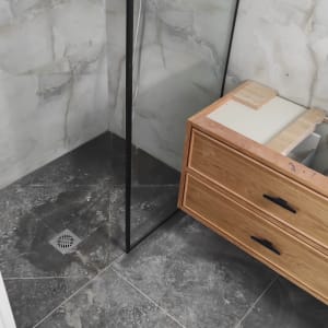 מקלחון זכוכית עם רצפה מלוכלכת וארון עץ