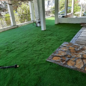 דשא סינתטי מתחת לפרגולה עם כלי גינון על הקרקע