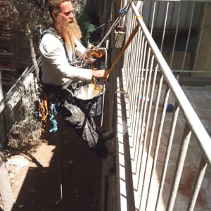 אדם תלוי על חבלים מבצע עבודת איטום חיצונית