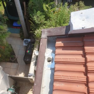 רעפים חומים על גג עם צינור מתכת